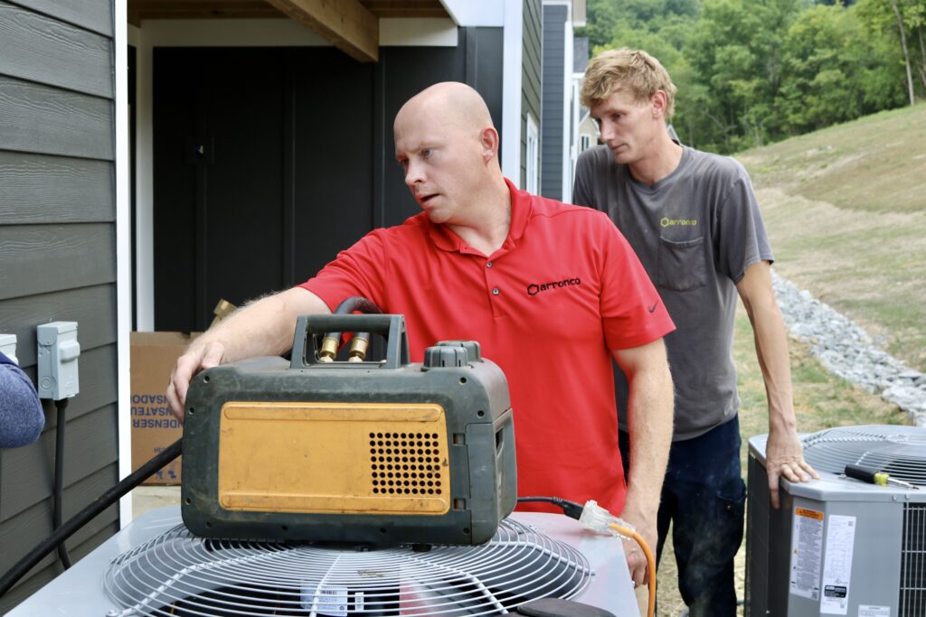 Two Arronco technicians servicing an outdoor HVAC unit